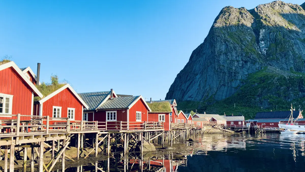 从雷讷 (Reine) 的游艇码头欣赏红色的传统渔屋 (Rorbu). 背景中的山峰就是雷讷布林根 (Reinebringen)